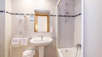 A bathroom with a sink, mirror, towel rack, and shower.