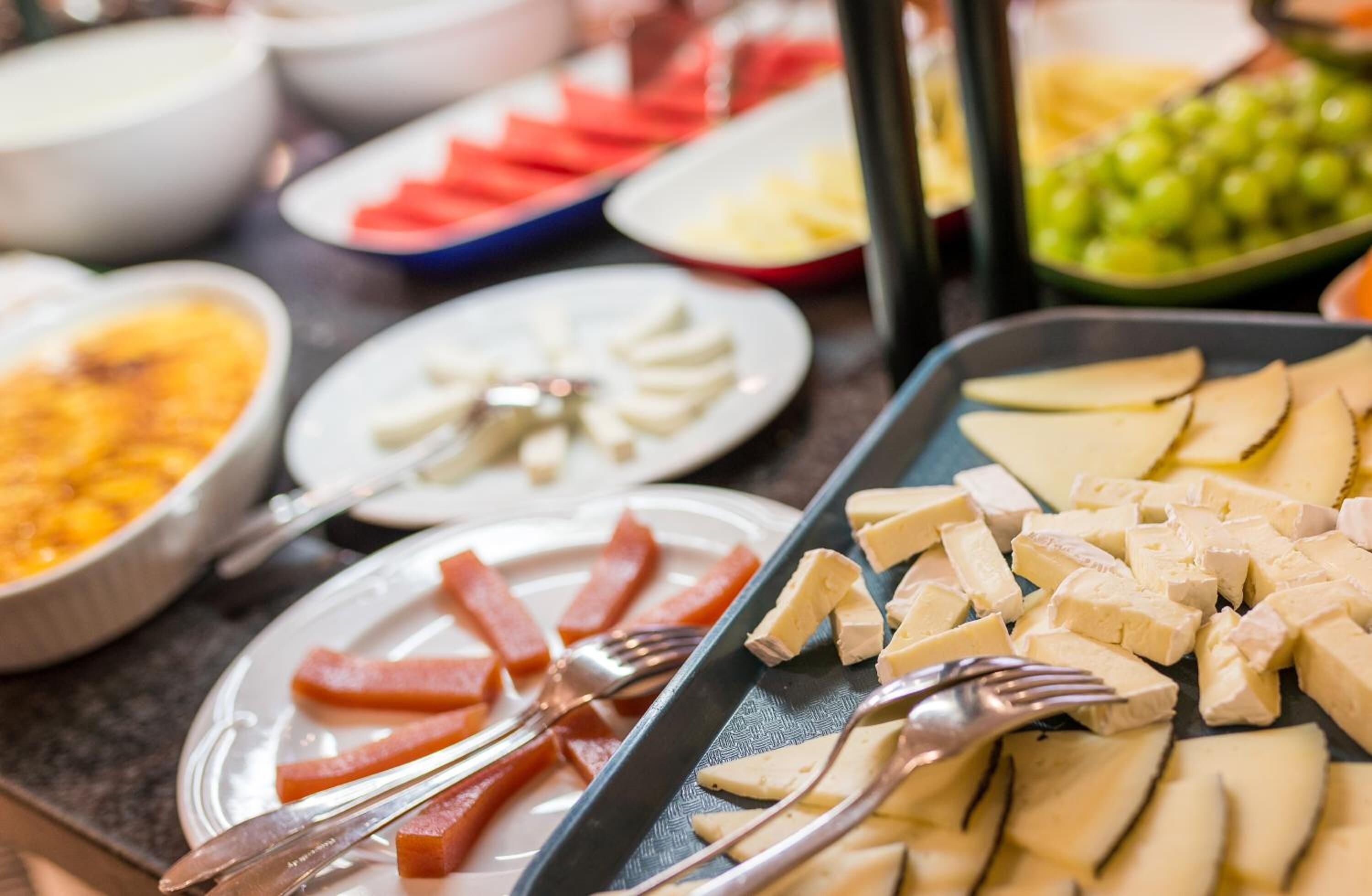 Un bufé con diversos alimentos, incluyendo rebanadas de manzana, queso y otras preparaciones.