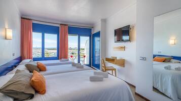 A hotel room with two beds, a TV, a desk, and a large window with a view.