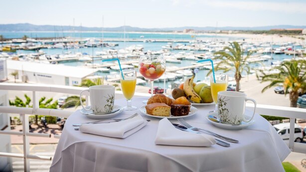 Una mesa de desayuno con vista a un puerto deportivo, con barcos y palmeras.