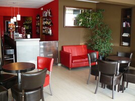 Un interior moderno con un sofá rojo, sillas negras, una pequeña mesa y una planta en maceta.