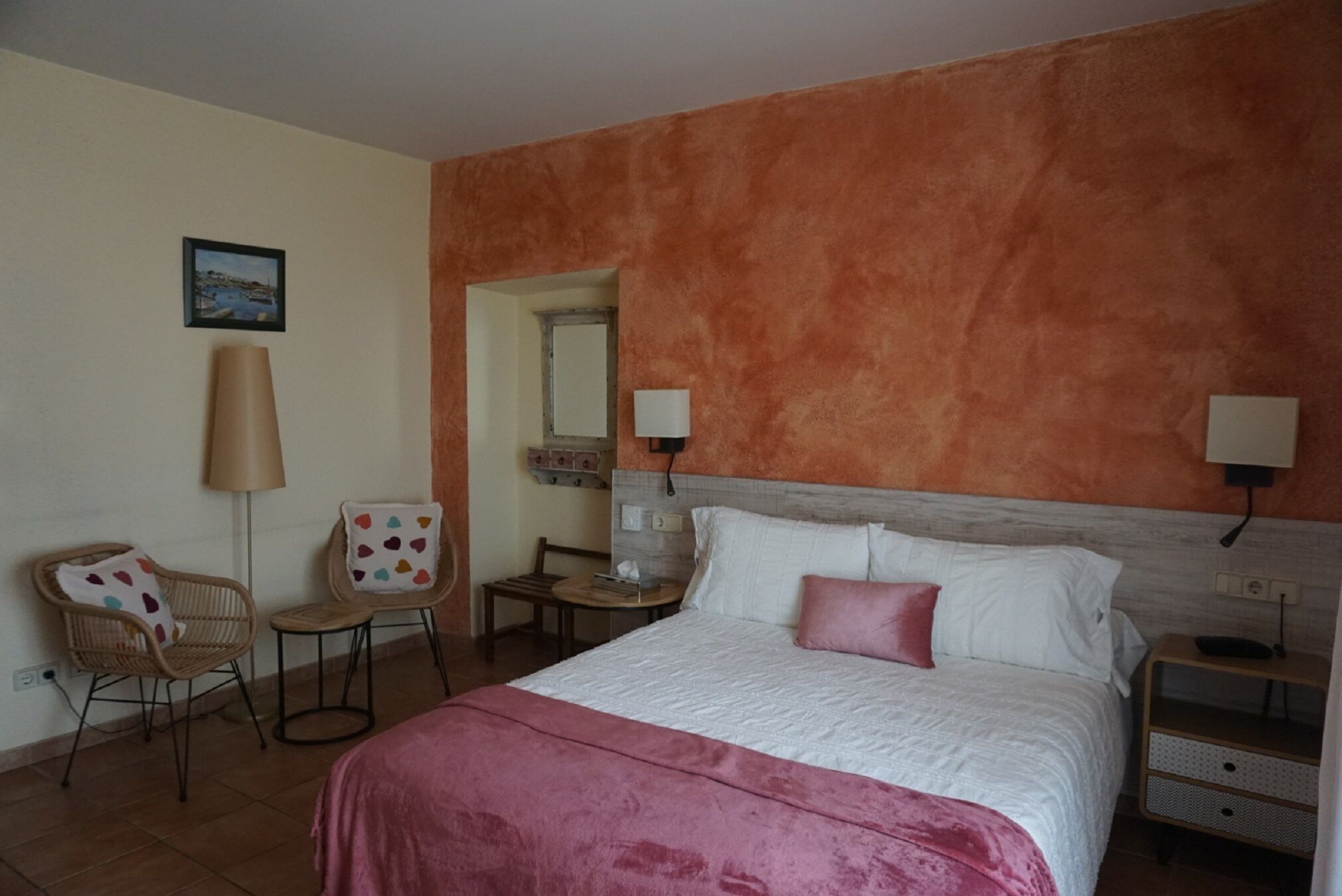 Un dormitorio con una cama, dos mesitas de noche, una lámpara y un cuadro en la pared.