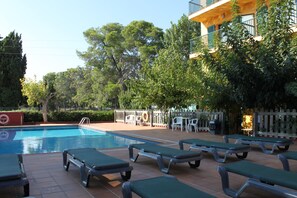 A swimming pool with lounge chairs and a fenced patio area with tables and chairs.