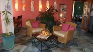 Un hall d’entrée accueillant, avec des meubles en osier, un panier de fruits sur une table basse et une plante en pot.