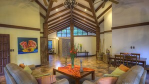 A spacious living area with a high ceiling, a fireplace, and a dining table with chairs. - Hacienda La Pacífica Eco-Lodge (Cañas)