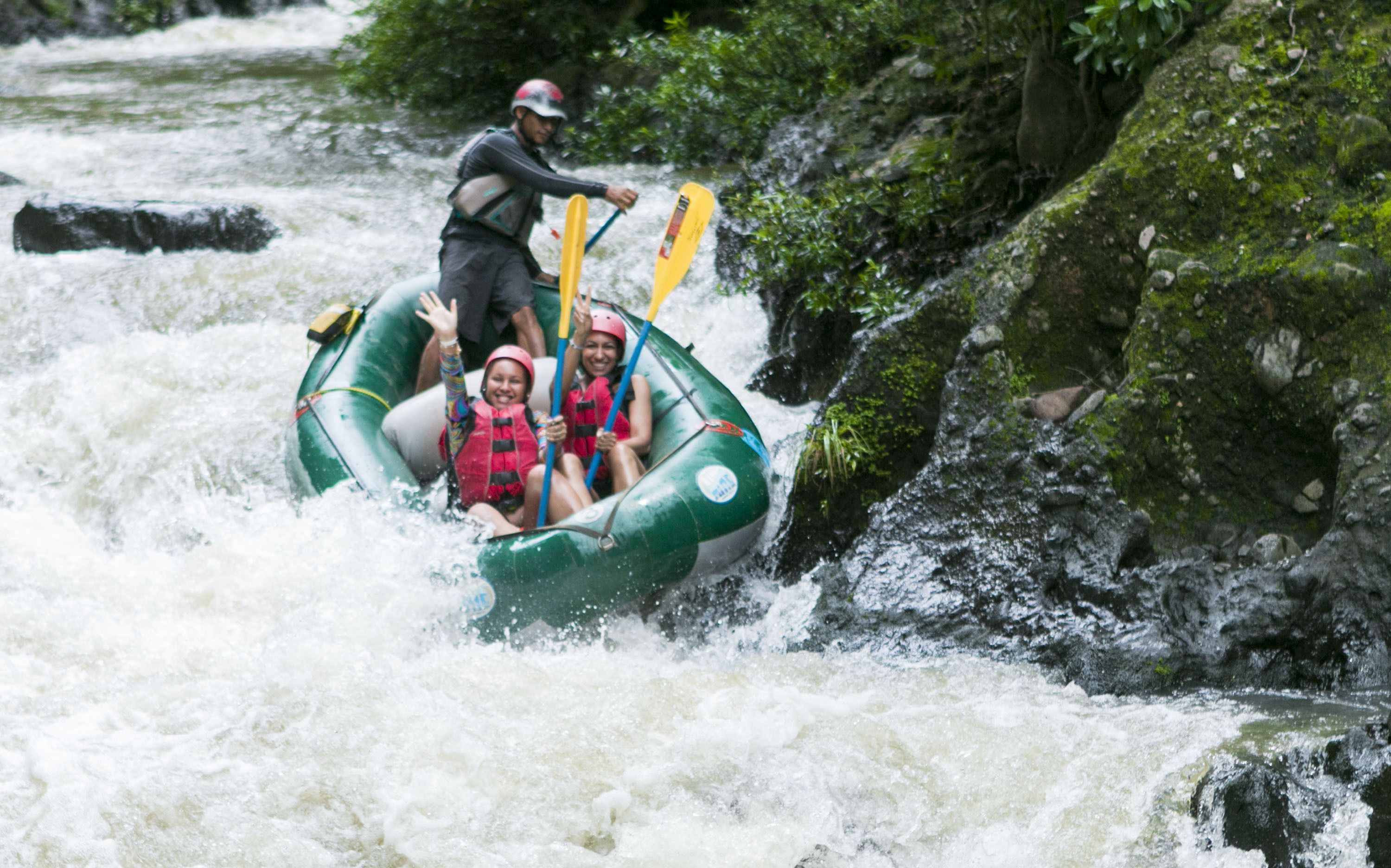 A river rafting activity with participants in a green raft navigating through rapids.