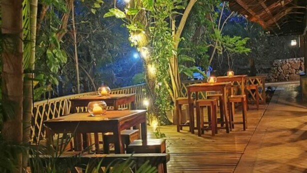 An outdoor dining area with wooden tables and chairs, surrounded by greenery and a stone wall. - Hacienda La Pacífica Eco-Lodge (Cañas)