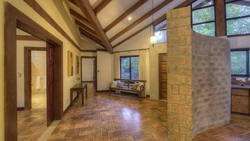 Un interior espacioso con chimenea de piedra, vigas de madera y ventanas grandes.