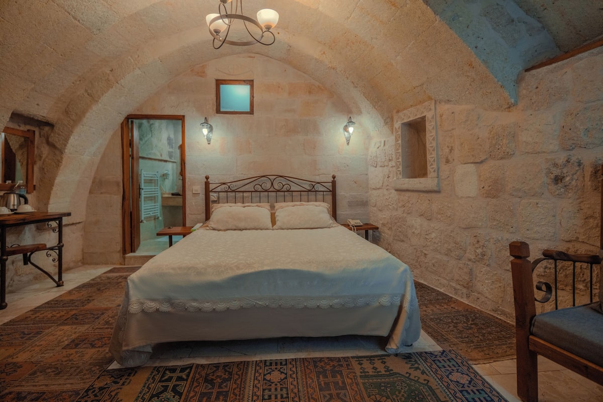 Un dormitorio con una cama grande, paredes de piedra y techo de madera.