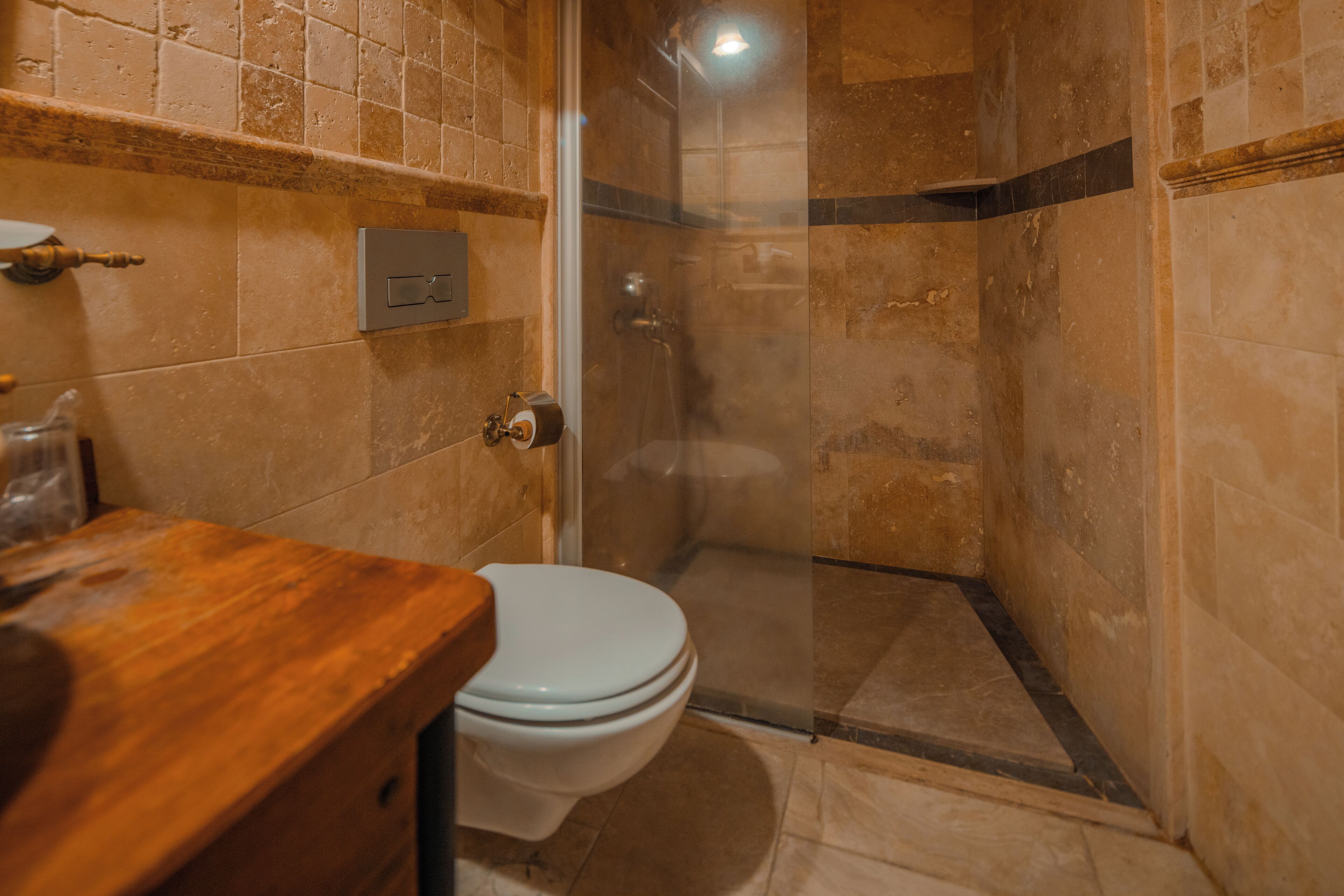 Un baño con ducha, inodoro y tocador de madera.
