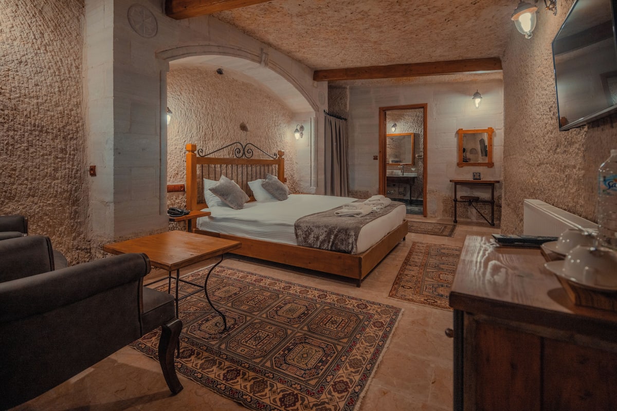Un dormitorio acogedor con una cama de madera, una mesita, una silla y un televisor.