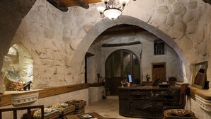 Une pièce rustique aux murs de pierre, avec des poutres en bois, un lustre, un bureau et des meubles de style traditionnel.