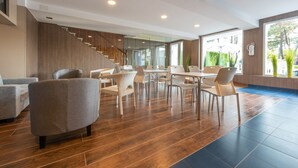 A modern hotel lobby with a wooden staircase, comfortable seating, and large windows offering a view of greenery. - Nuevo Norat Sanxenxo (Sanxenxo)