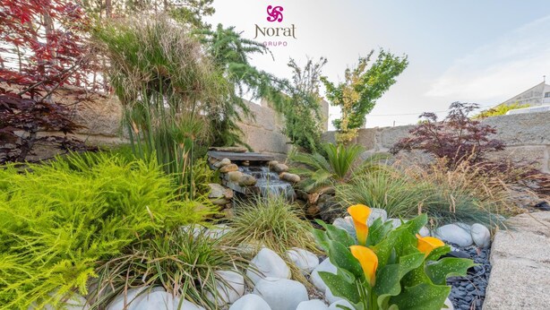 A landscaped garden with a water feature, various plants, and a stone wall. - Nuevo Norat Sanxenxo (Sanxenxo)