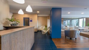 A modern reception area with a wooden reception desk, pendant lighting, and a blue accent wall. - Nuevo Norat Sanxenxo (Sanxenxo)