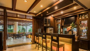 A bar area with wooden bar stools, a television, and a glass display case with trophies.