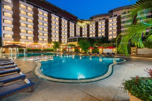 A hotel with a swimming pool, sun loungers, and a covered area with umbrellas. - Mountain Beach Resort (Pattaya)