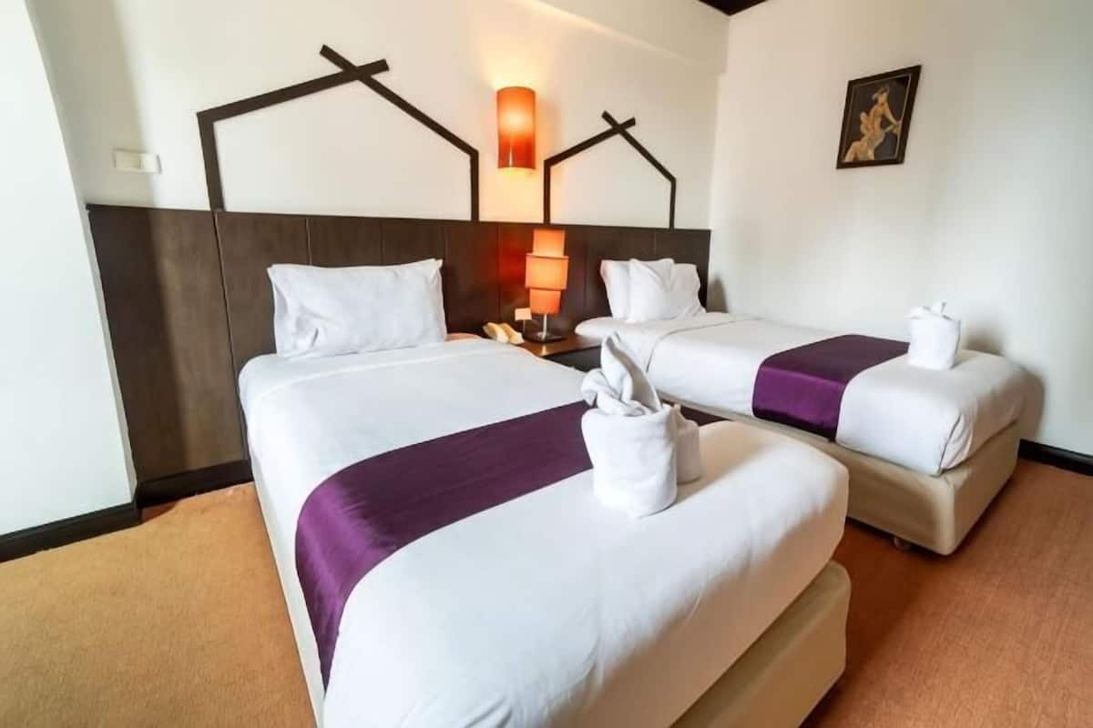 Quarto de hotel com duas camas, uma mesa de cabeceira, uma luminária e um quadro na parede.