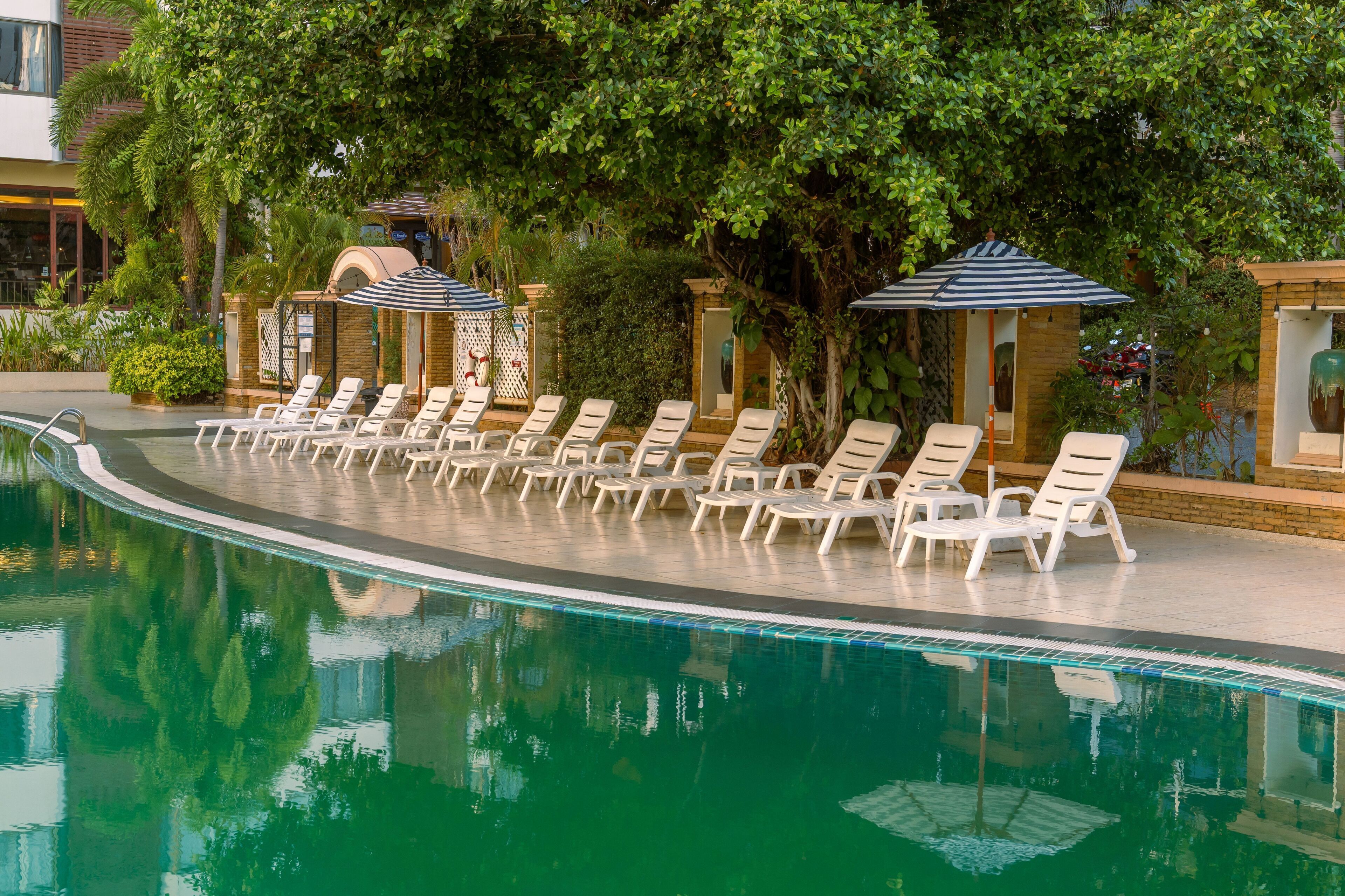 Área de piscina com espreguiçadeiras e guarda-sóis.