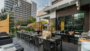 An outdoor dining area with wicker furniture and a buffet setup. - Mountain Beach Resort (Pattaya)