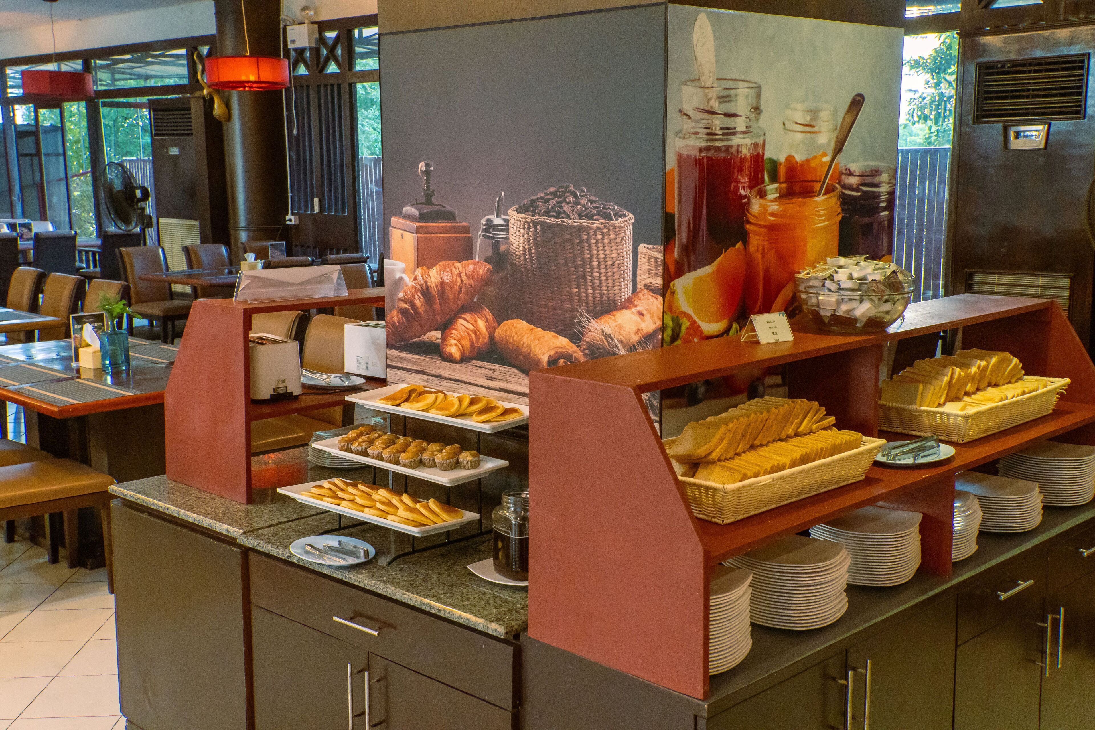 A breakfast buffet with various food items and a large poster of coffee and pastries.