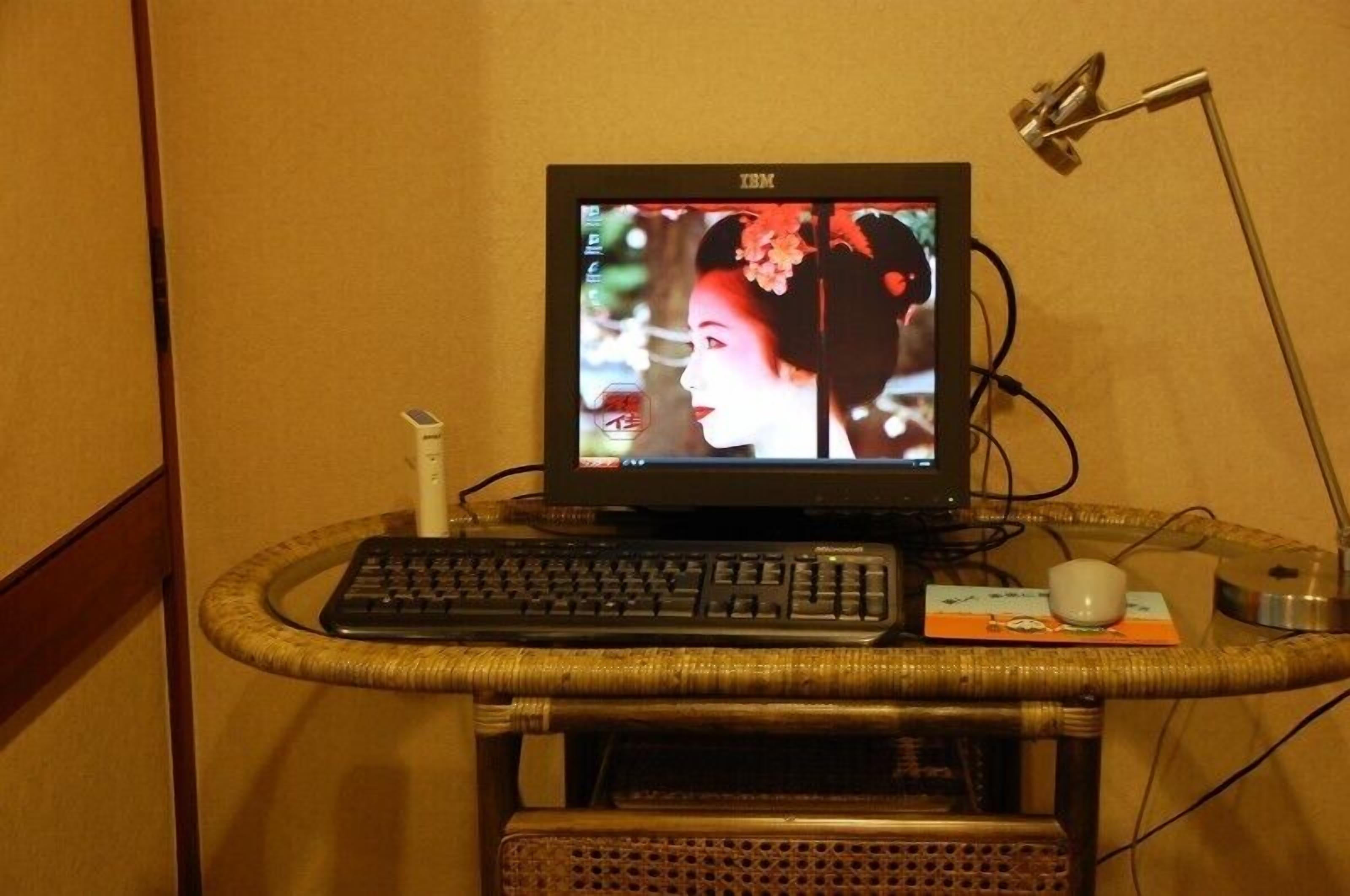 A television on a stand with a keyboard and mouse, connected to a lamp.