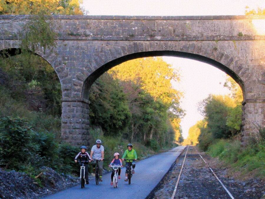 A stone bridge over railway tracks with cyclists.