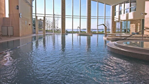 An indoor swimming pool with clear views of the outdoors, large windows, and a modern architectural design. - Hodson Bay Hotel (Athlone)