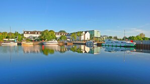 A marina with boats docked, a modern building, and a traditional house in the background. - Hodson Bay Hotel (Athlone)