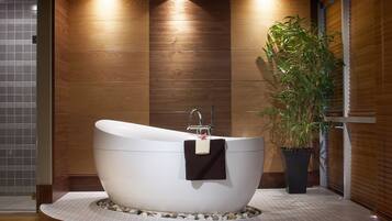 Un baño moderno con una bañera independiente, una planta en maceta y paneles de madera.