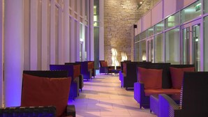 A corridor with seating areas, a stone wall, and large windows. - Hodson Bay Hotel (Athlone)