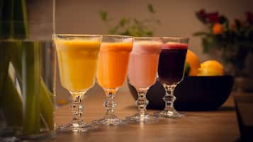 Four glasses of different colored beverages on a wooden table.