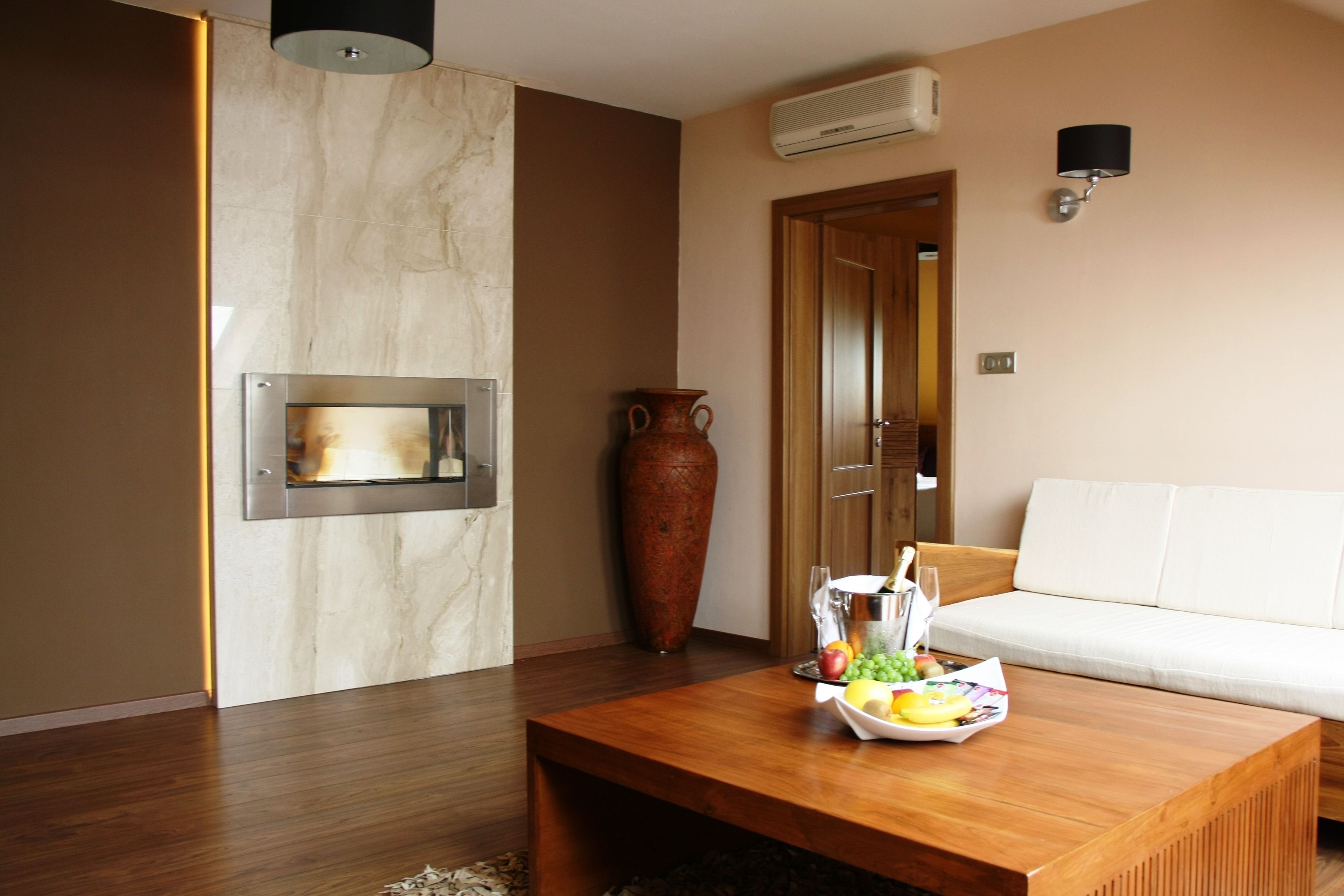 A modern living room with a wooden coffee table, a white sofa, a large vase, and a fireplace.