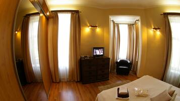 Una habitación de hotel con una cama grande, un aparador, un televisor y cortinas.