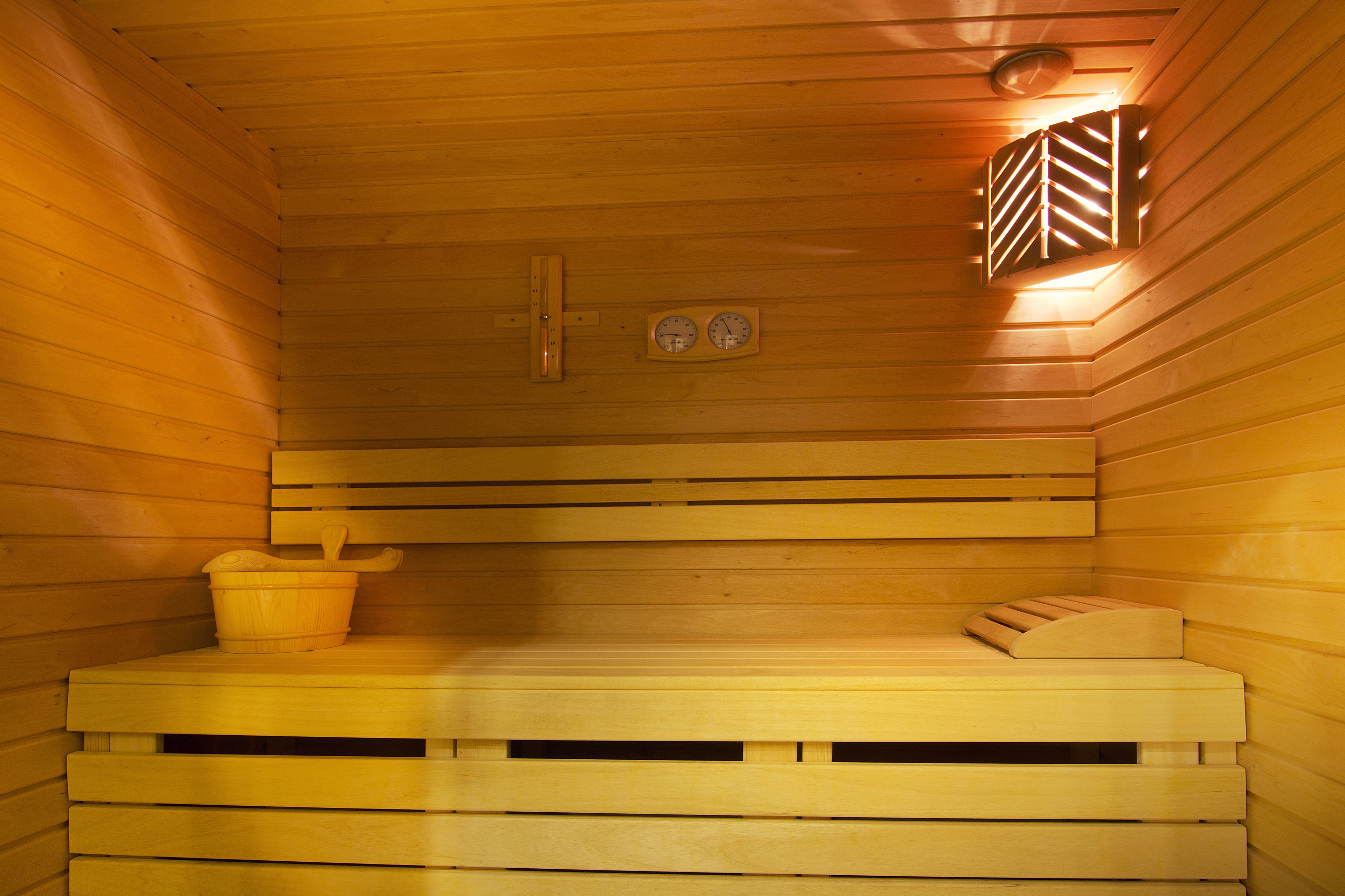 Una sauna de madera con bancos, un balde y un termómetro.
