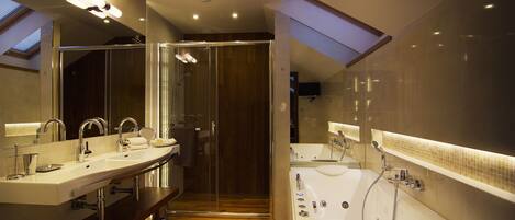 Un baño moderno con dos lavamanos, una bañera grande y un box de ducha de cristal.