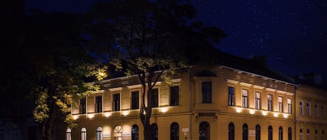 A historic building with arched windows and a central entrance, illuminated by street lighting.