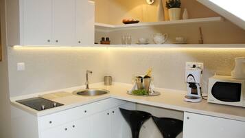 A modern kitchen with white cabinets, a sink, a coffee machine, and a microwave.