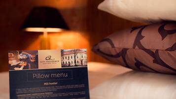 Carta de almohadas del Apart Hotel City Residence, mostrando una cama con almohadas estampadas y una lámpara al fondo.