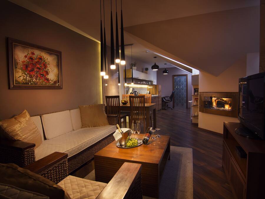 Ein modernes Wohnzimmer mit einer Couch, einem Couchtisch mit einer Champagnerflasche und Gläsern, einem Fernseher und einem Kamin.