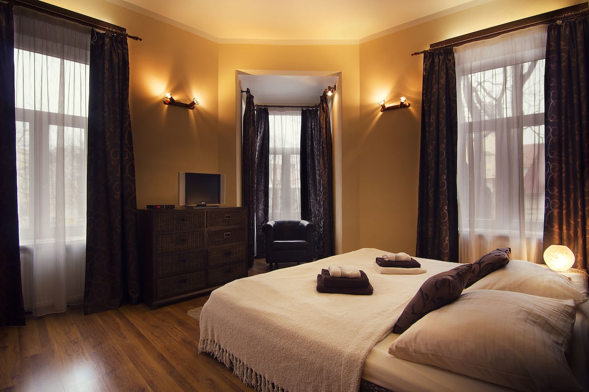 A hotel room with a large bed, a dresser, a chair, and a desk with a computer.
