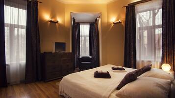 A hotel room with a large bed, a dresser, a chair, and a desk with a computer.