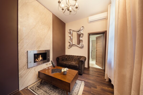 A modern living room with a fireplace, a leather sofa, a wooden coffee table, and a decorative mirror.