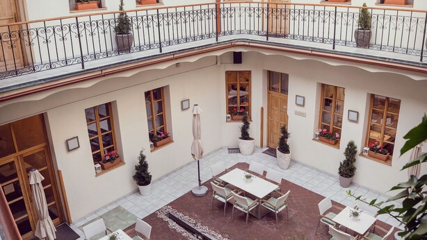 Une cour avec des espaces de détente en plein air, des plantes en pot et un balcon agrémenté de balustrades.