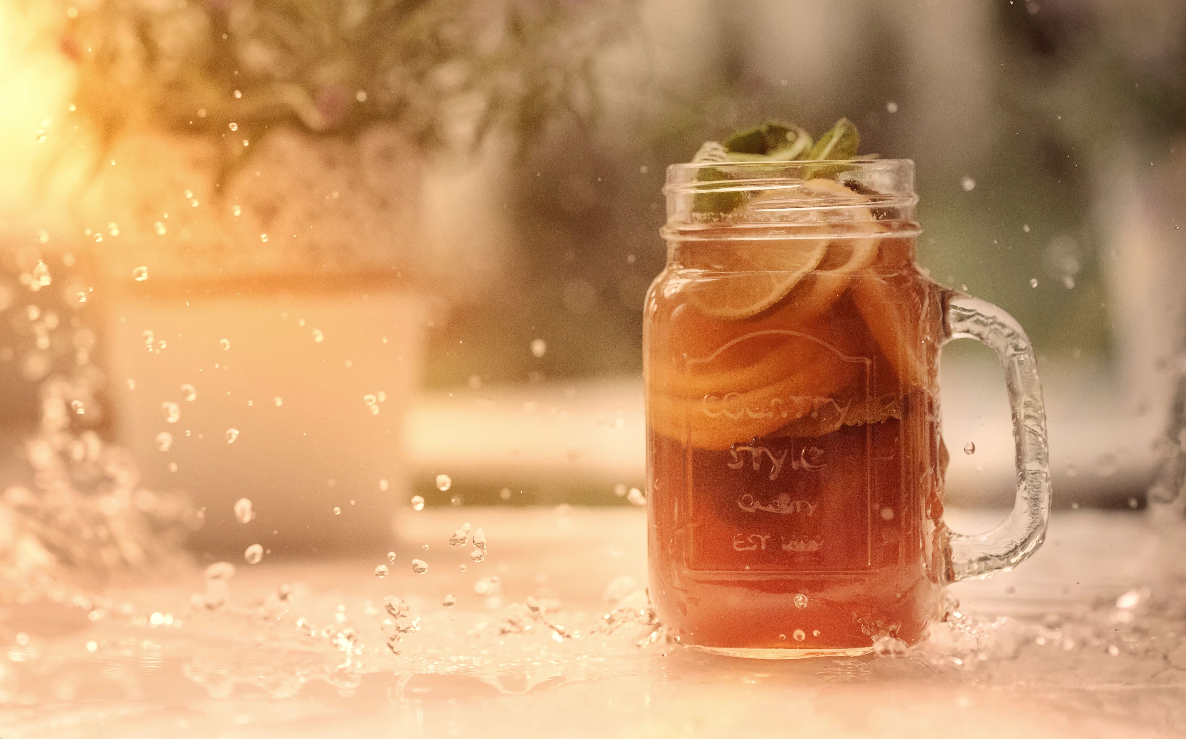 A clear glass mug filled with a beverage, possibly tea, with a mint leaf garnish.