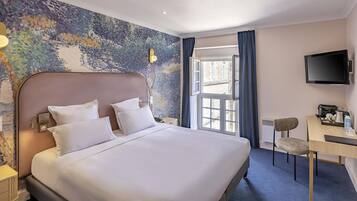 Quarto de hotel com uma cama grande, uma mesa, uma cadeira, uma televisão e uma janela com cortinas.