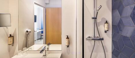 Een moderne badkamer met een grote spiegel, een wastafel en een douche.
