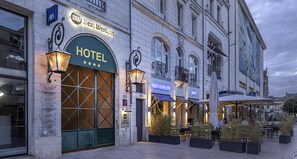 Un hotel con una amplia entrada arqueada, zona de estar al aire libre y un restaurante contiguo.