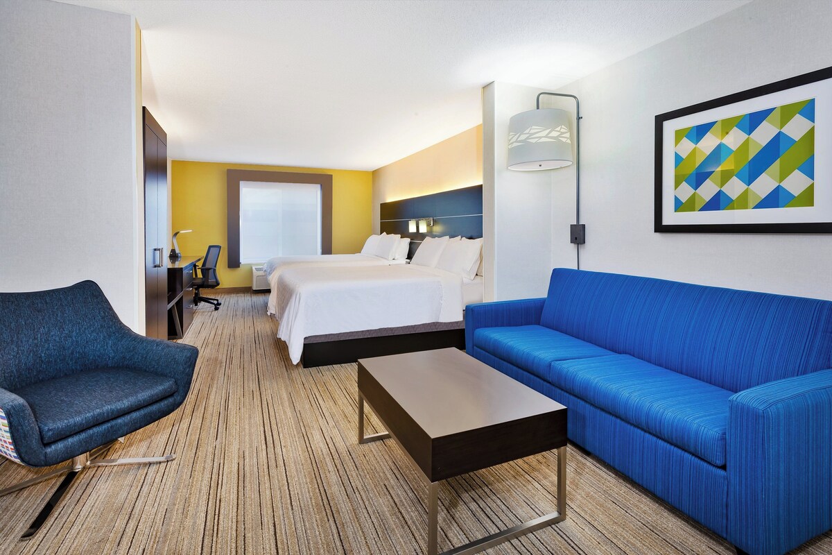 Una habitación de hotel con una cama, un sofá azul, un escritorio y una silla.