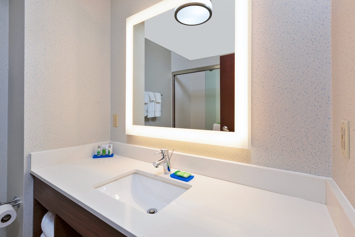 A bathroom with a white sink, a mirror, and a towel rack.